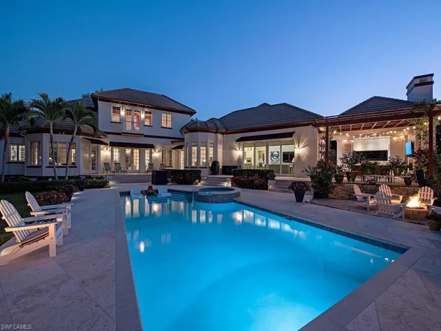 Pool at dusk featuring a patio area, an in ground hot tub, and an outdoor fire pit