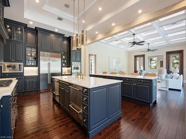 Kitchen with pendant lighting, coffered ceiling, a center island with sink, built in appliances, and beam ceiling