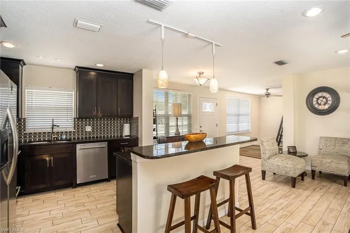 Kitchen with rail lighting, a kitchen island, appliances with stainless steel finishes, decorative backsplash, and pendant lighting