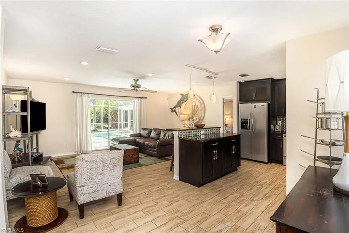 Kitchen featuring light hardwood / wood-style flooring, a kitchen island, ceiling fan, pendant lighting, and stainless steel fridge