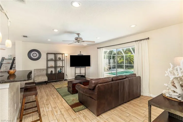 Living room featuring a textured ceiling, light wood-type flooring, and ceiling fan