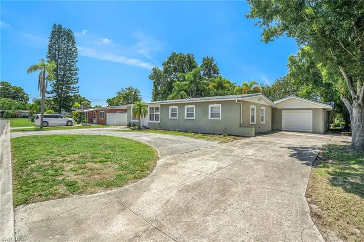 Ranch-style house featuring a garage, an outbuilding, and a front lawn