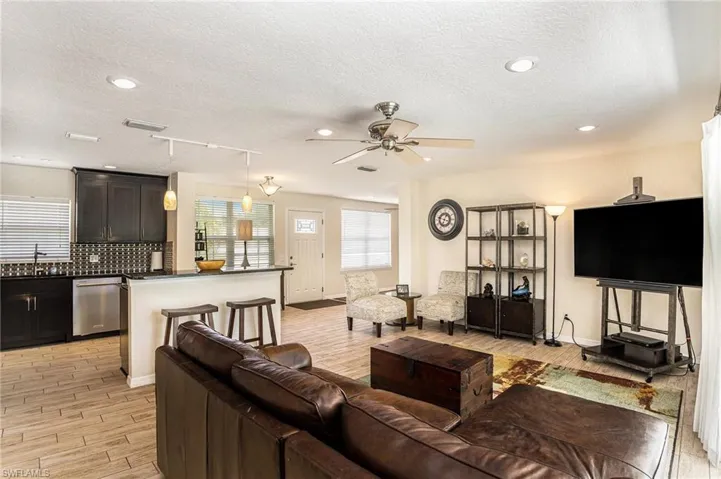 Living room with track lighting, sink, light wood-type flooring, a textured ceiling, and ceiling fan