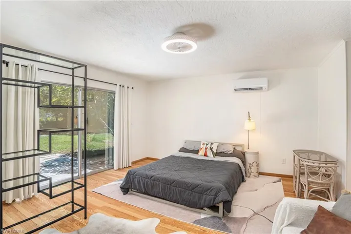 Bedroom featuring an AC wall unit, hardwood / wood-style floors, and a textured ceiling