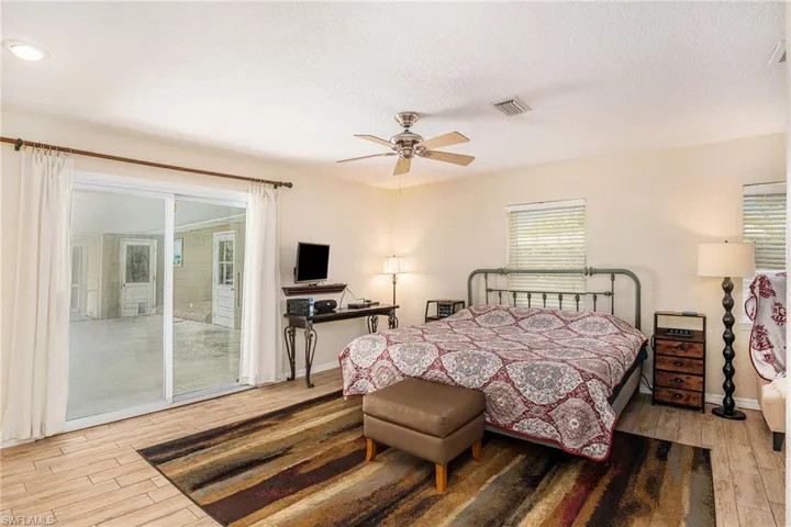Bedroom featuring hardwood / wood-style floors, a textured ceiling, ceiling fan, and access to exterior