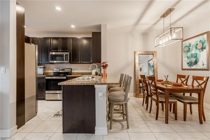 Kitchen with a kitchen breakfast bar, a peninsula, light stone countertops, stainless steel appliances, and a sink