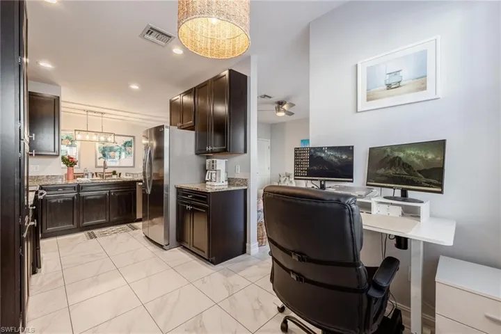 Kitchen featuring freestanding refrigerator, marble finish floor, a sink, and dark brown cabinets