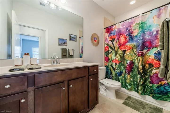 Full bathroom with toilet, tile patterned flooring, vanity, and visible vents
