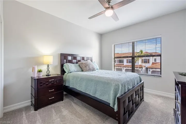 Bedroom featuring light carpet, ceiling fan, and baseboards