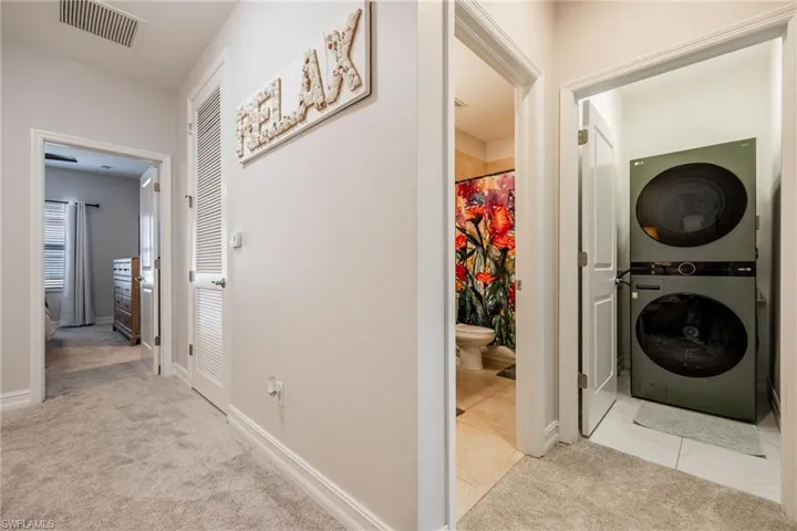 Washroom with laundry area, baseboards, visible vents, stacked washer / dryer, and carpet