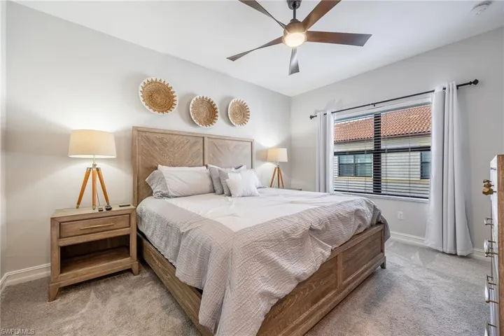 Bedroom with light carpet, ceiling fan, and baseboards