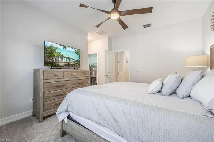 Bedroom featuring a walk in closet, visible vents, attic access, light carpet, and baseboards