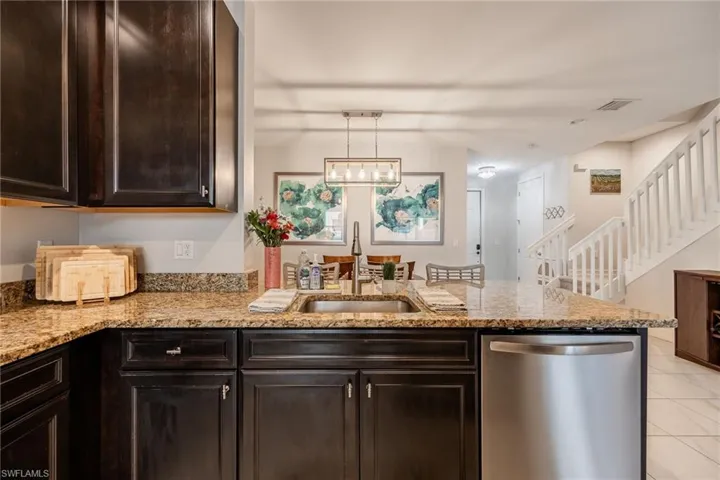 Kitchen with visible vents, a sink, light stone countertops, dishwasher, and a peninsula