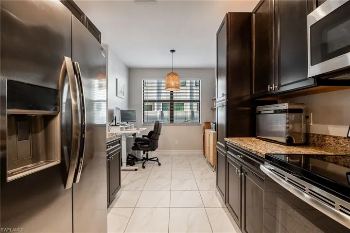 Kitchen with marble finish floor, stainless steel appliances, hanging light fixtures, and light stone countertops