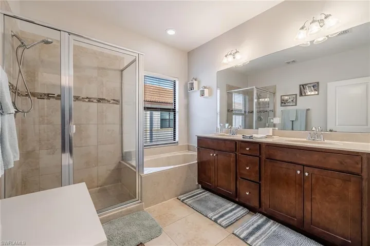Full bathroom featuring double vanity, a garden tub, tile patterned flooring, a shower stall, and a sink