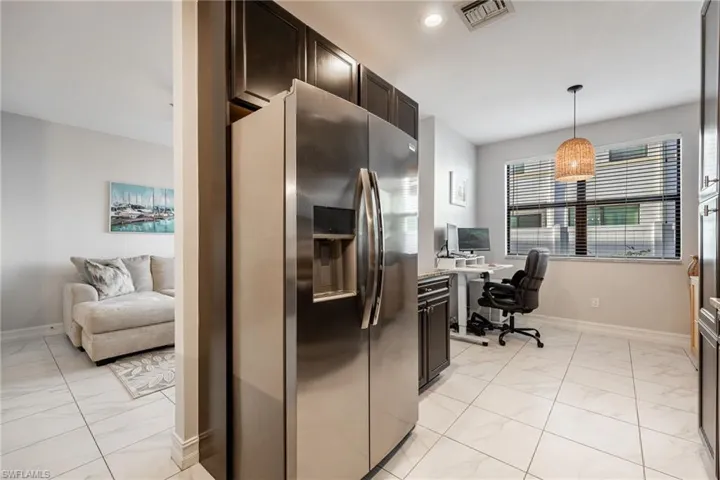Kitchen with baseboards, visible vents, dark brown cabinets, and stainless steel fridge with ice dispenser