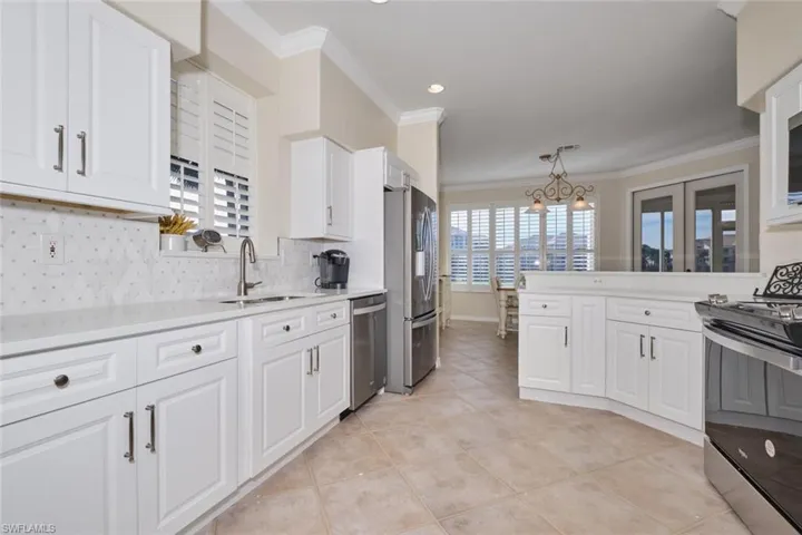 Kitchen with sink, stainless steel appliances, backsplash, crown molding, and decorative light fixtures