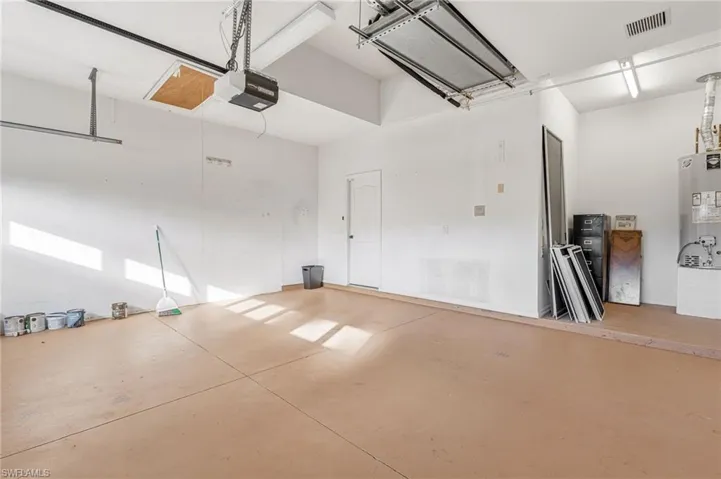 Two-car garage featuring a light-toned concrete floor, white painted walls, and an automatic garage door opener