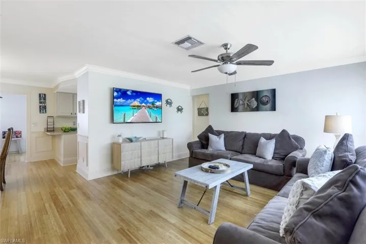 Living area featuring a ceiling fan, ornamental molding, and light wood-style floors