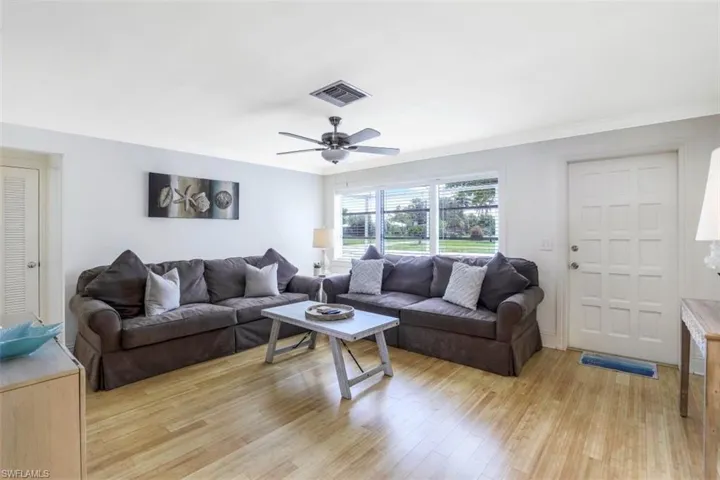 Living area with light wood-style flooring, a ceiling fan, and crown molding
