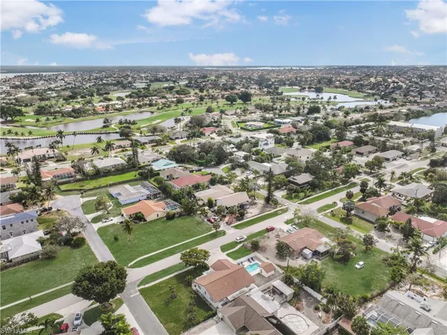 View of property location featuring a nearby body of water, nearby suburban area, and a golf club