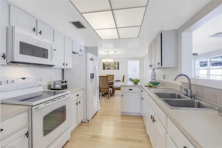 Kitchen featuring white appliances, light countertops, light wood-style floors, and white cabinetry