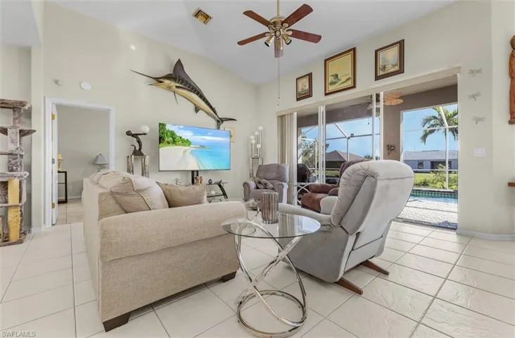 Living room featuring light tile patterned floors, ceiling fan, baseboards, and plenty of natural light
