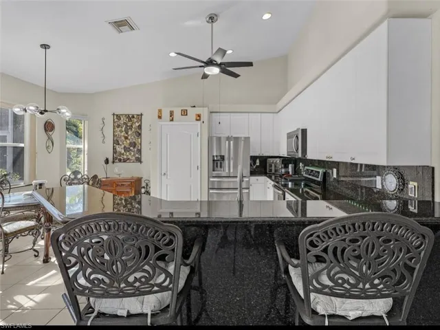 Kitchen with ceiling fan, visible vents, backsplash, white cabinets, and appliances with stainless steel finishes