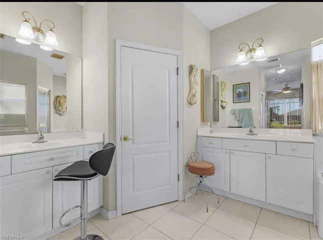 Full bathroom featuring two vanities, a sink, tile patterned floors, and visible vents
