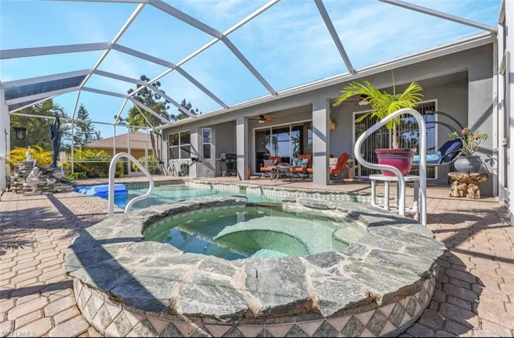 View of swimming pool featuring a lanai, ceiling fan, a pool with connected hot tub, and a patio area