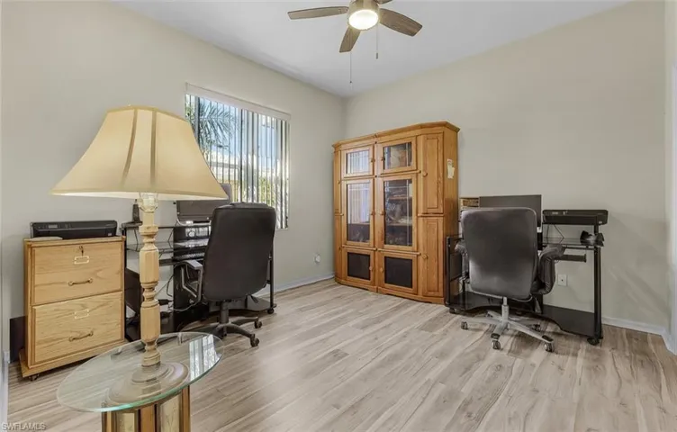 Office area with baseboards, ceiling fan, and light wood finished floors