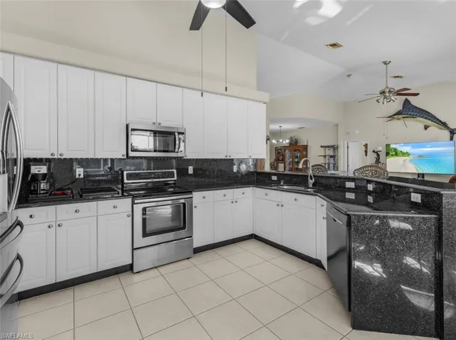 Kitchen featuring a ceiling fan, a sink, appliances with stainless steel finishes, and tasteful backsplash