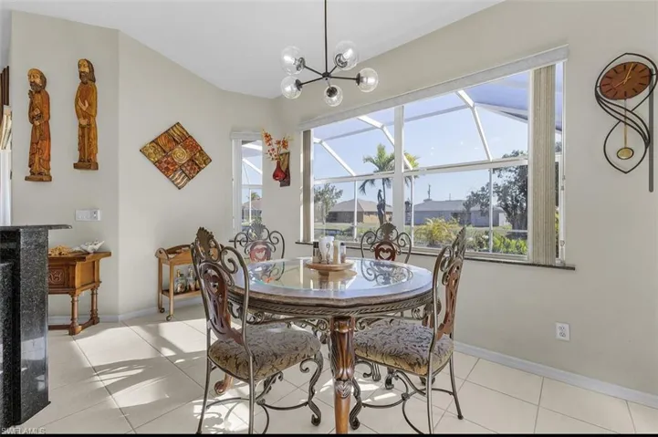 Dining space featuring baseboards, light tile patterned floors, and a notable chandelier