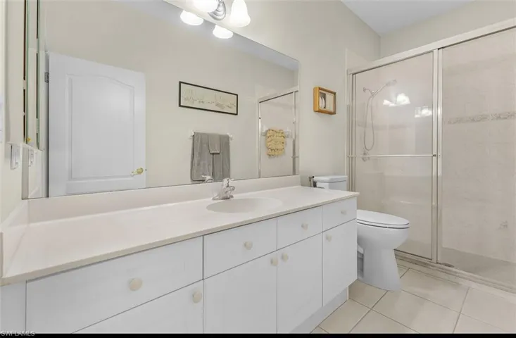 Bathroom with toilet, a stall shower, tile patterned flooring, and vanity
