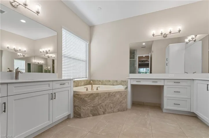 Primary Bathroom featuring dual vanities and a relaxing tiled tub