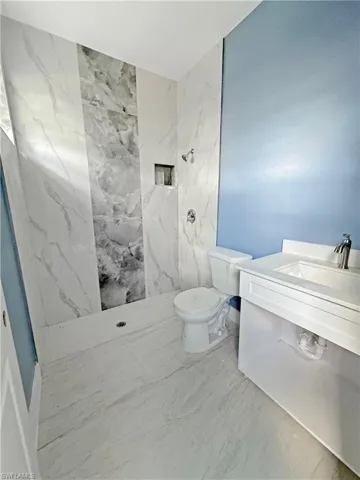 Bathroom featuring vanity and a marble finish shower