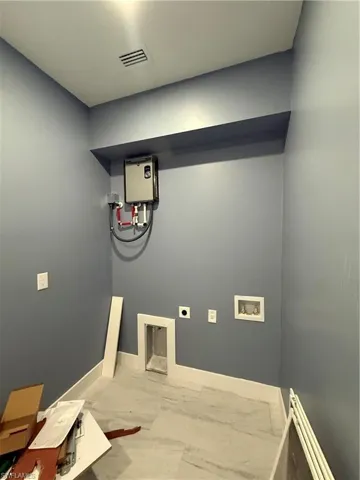 Washroom with hookup for a washing machine, electric dryer hookup, water heater, marble look tiles, and a baseboard radiator