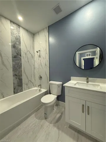 Bathroom with vanity, a combined bath / shower with marble appearance, and light marble finish floors