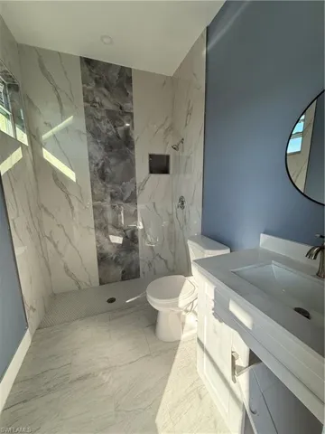 Full bath with a marble finish shower, vanity, and light marble finish floors
