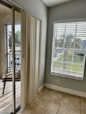 Doorway with light tile patterned flooring and baseboards
