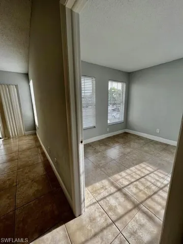 Hall with tile patterned flooring, a textured ceiling, and baseboards