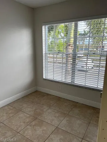 Spare room with baseboards, light tile patterned floors, and a wealth of natural light