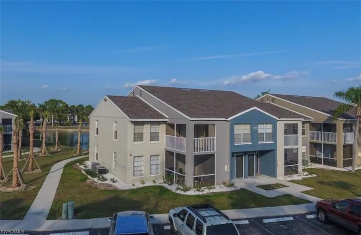 Back of house with stucco siding, uncovered parking, a water view, and a balcony