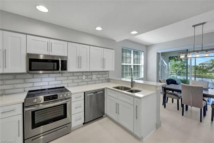 Open Kitchen with Quartz counters, decorative tile backsplash, stainless appliances, breakfast bar peninsula,and recessed lighting