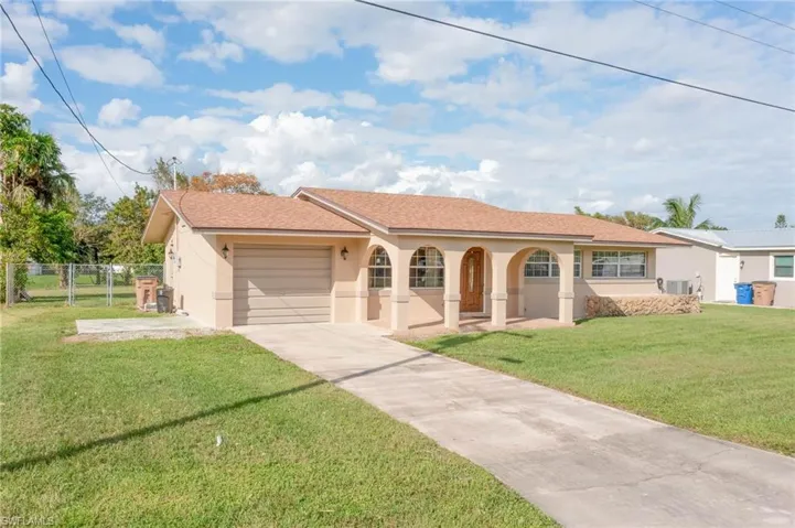View of front facade featuring a front lawn, cooling unit, and a garage