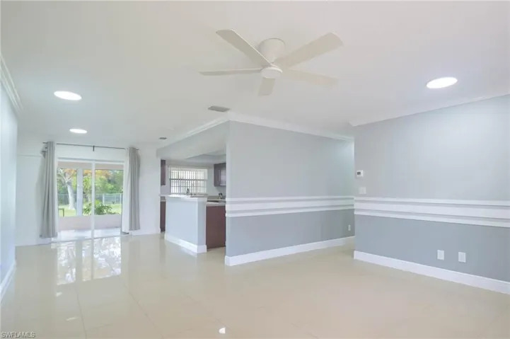 Tiled empty room with ceiling fan and ornamental molding