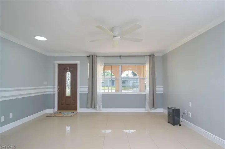 Tiled foyer entrance featuring ornamental molding and ceiling fan