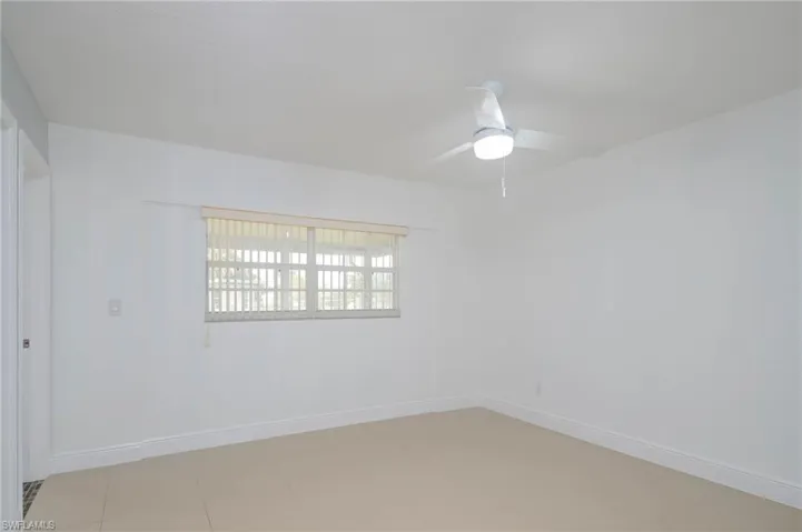 Empty room with light tile patterned flooring and ceiling fan