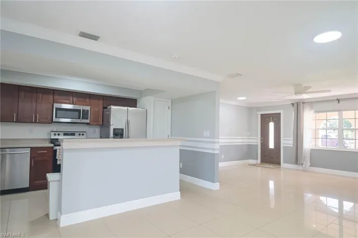 Kitchen featuring ceiling fan, appliances with stainless steel finishes, light tile patterned floors, and a kitchen island
