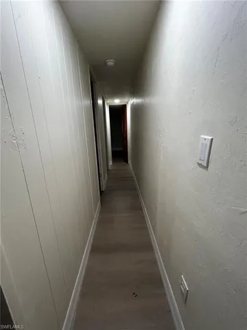 Corridor with hardwood / wood-style floors and wooden walls